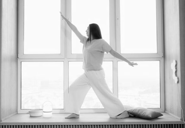 Woman practicing yoga indoors, in a stylish black and white ambiance.