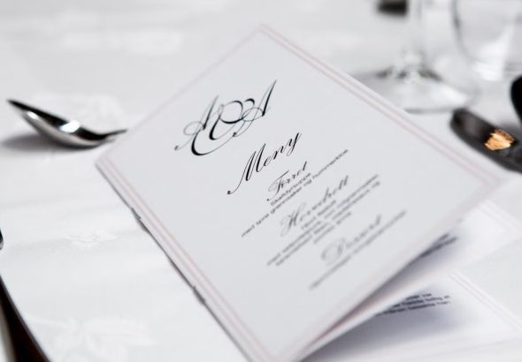 Close-up of a refined dining table with menu and silverware, showcasing elegance in a formal restaurant setting.