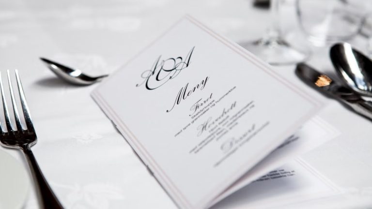 Close-up of a refined dining table with menu and silverware, showcasing elegance in a formal restaurant setting.