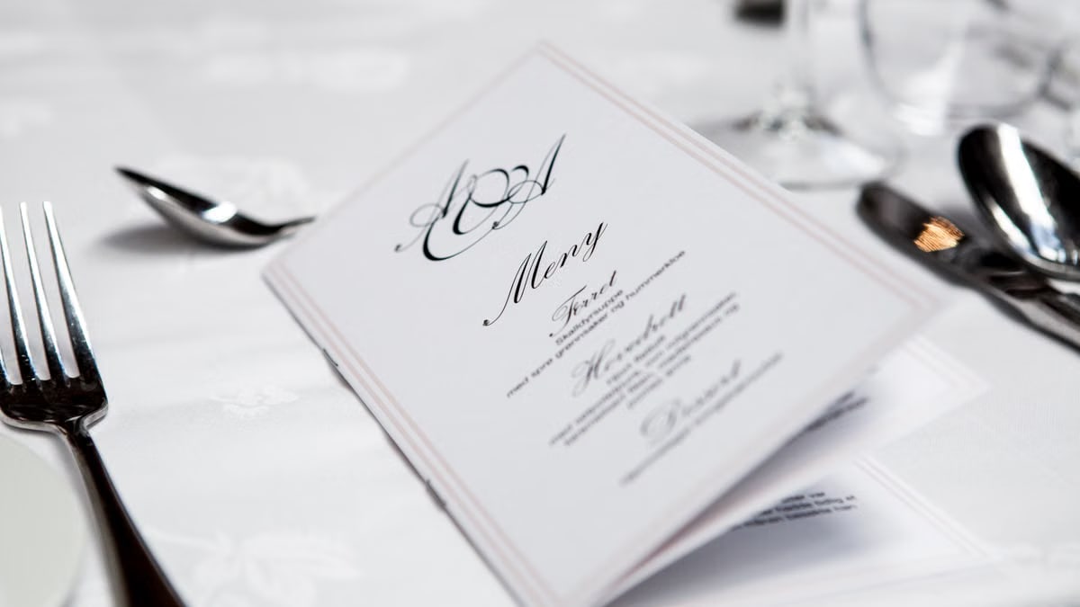 Close-up of a refined dining table with menu and silverware, showcasing elegance in a formal restaurant setting.